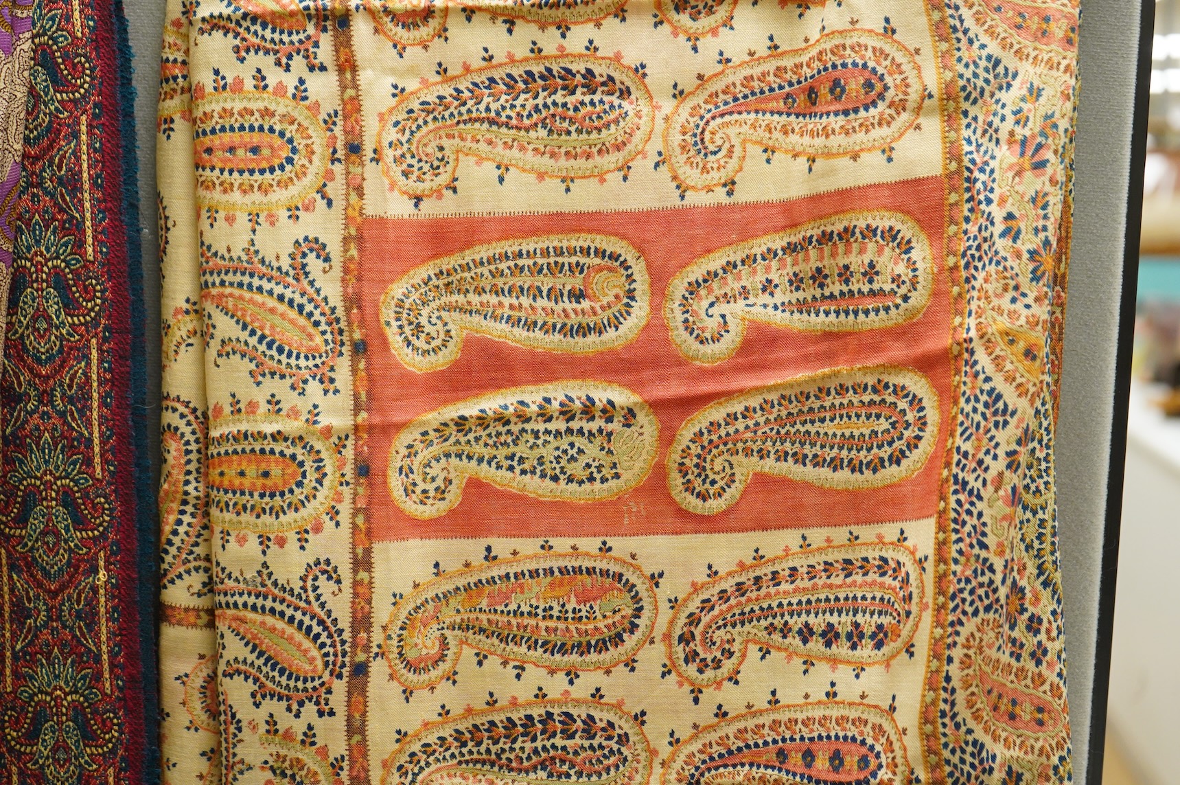 A 19th century printed silk shawl and a printed paisley shawl, together with a late 20th century wool machine woven stole with Oswal label. Condition - the two 19th century shawls are damaged but useful for TV and film c